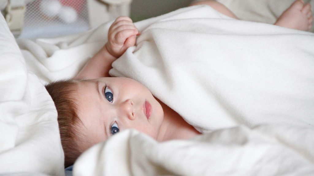 Baby unter einer Decke beim Besuch des Kinderarztes bei der U3 Untersuchung