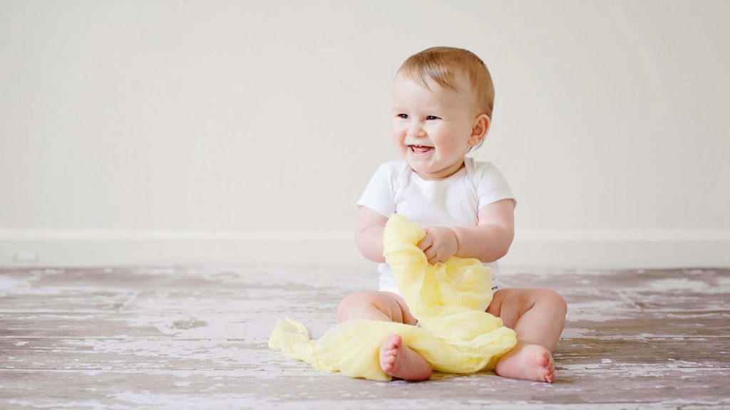 Lachendes Baby mit einer Kuscheldecke