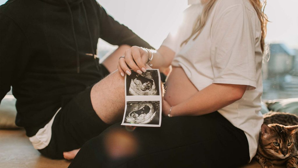 Paar zeigt die Entwicklung des Embryos mit Ultraschallbildern. 