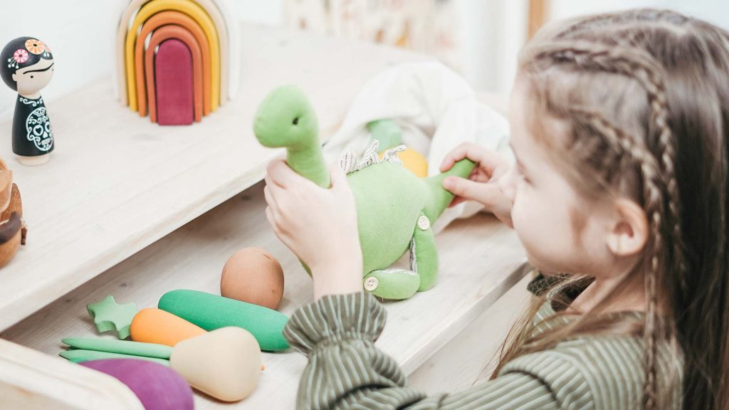 Kleinkind mit Spielzeug Dinosaurier.