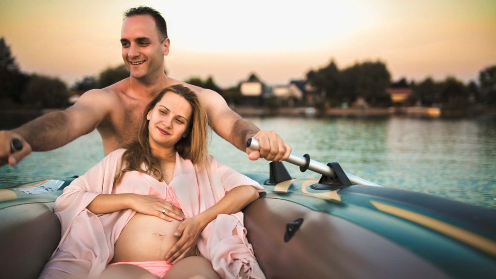 Schwangere Frau und Mann im Ruderboot auf Fluss