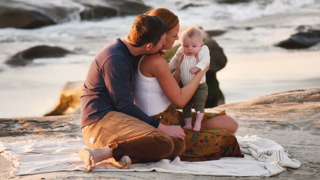 Junge Familie ist im ersten Urlaub mit Baby und picknicken am Strand