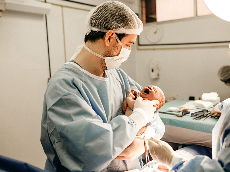 Frisch gebackener Papa hält sein neugeborenes Baby nach Kaiserschnitt im Arm