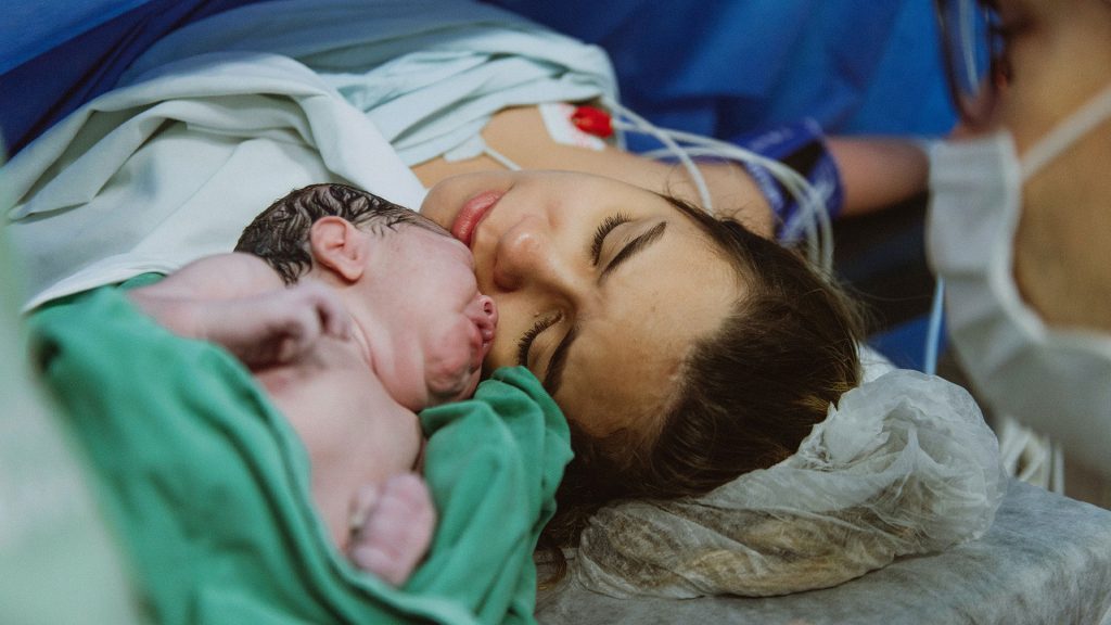 Erster Hautkontakt zwischen neugeborenem Baby und Mama nach der Geburt