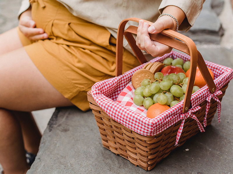 Schwangere Frau mit Obst-Picknick Korb